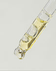 Glass dropper with a clear liquid on a light gray background