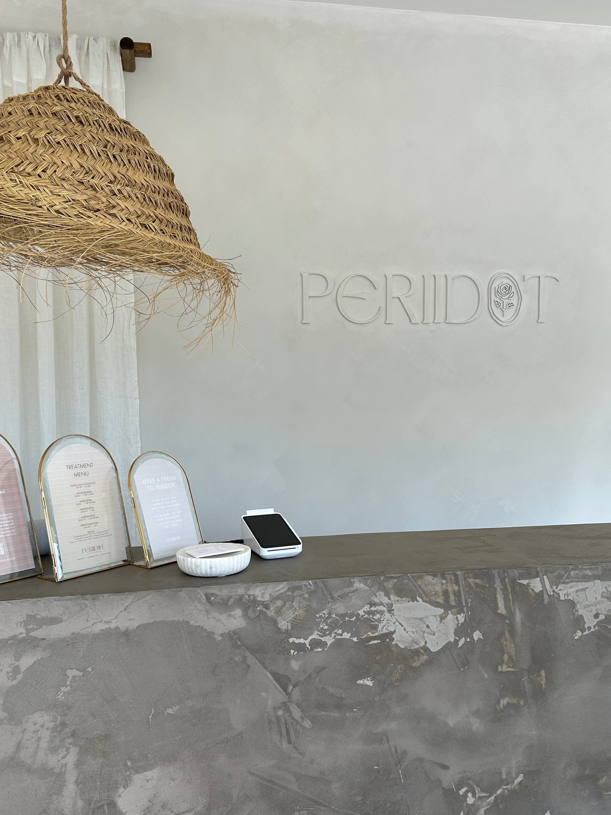 White surface with 'PERIIDOT' branding, a front desk, and decorative items.
