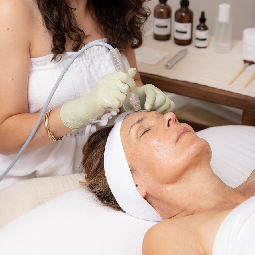 Woman receiving a facial treatment from another woman in a clinical setting.